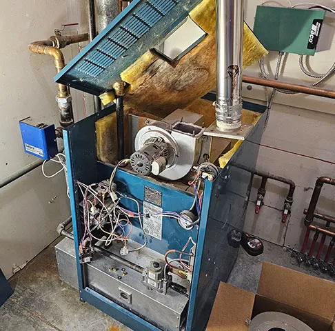 A boiler opened up in a mechanical room for an inducer motor replacement
