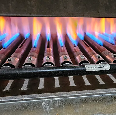 A row of gas burners firing with blue flames