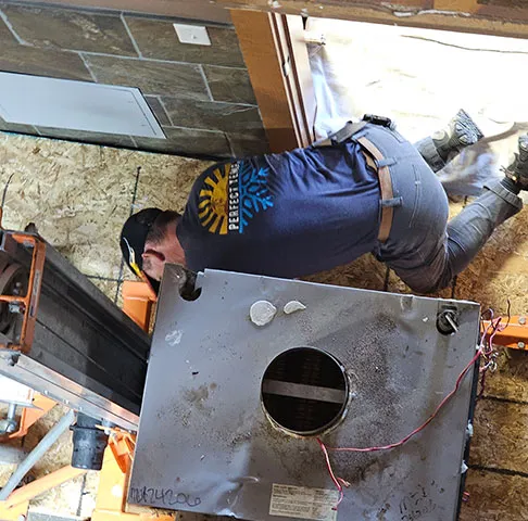 A Perfect Temp technician in an attic beside a unit raised on a lift