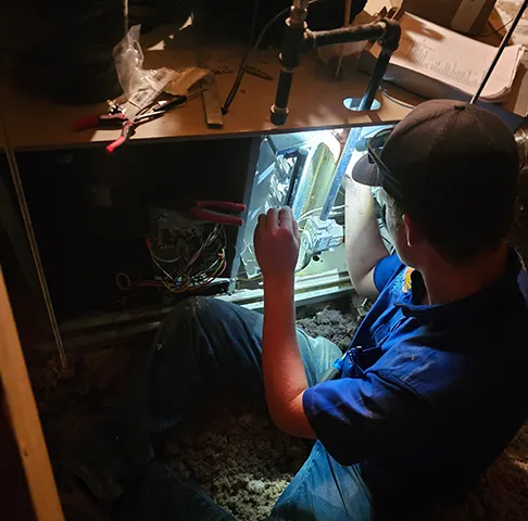 A Perfect Temp technician working on a unit by flashlight